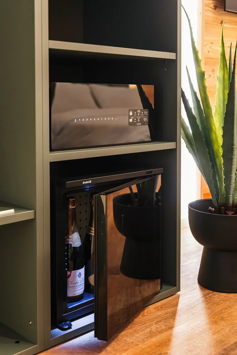 Il minibar e la cassaforte nel mobile del Sole, accanto a una pianta.