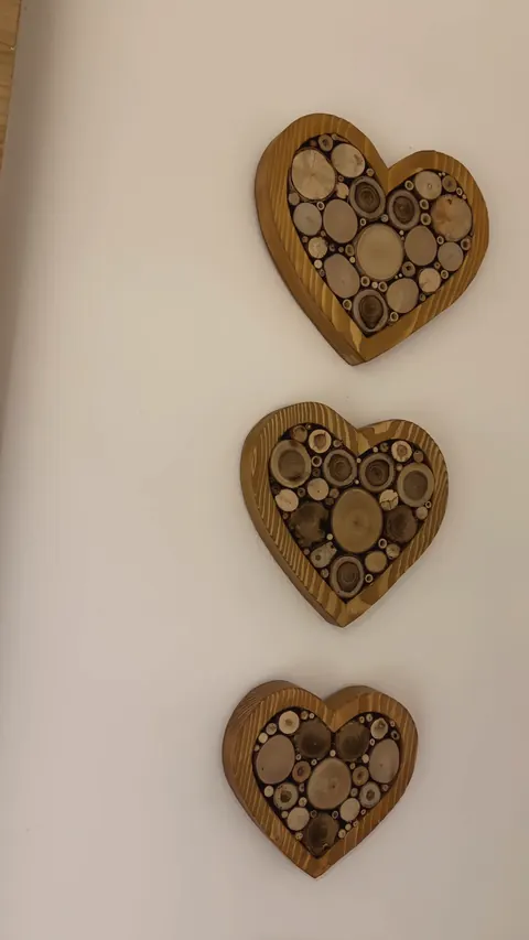 Tre cuori di legno riempiti di rondelle di tronco, uno sopra l'altro sulla parete chiara della camera della Luna.
